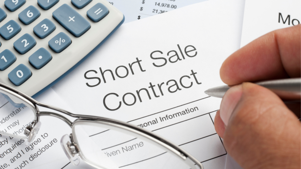 a picture of someone writing on a paper that says "short sale contract" with glasses and a calculator